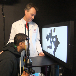 Photo of Dr. Hendrik Scholl conducting an electroretinogram, or ERG, with a patient at the Wilmer Eye Institute.