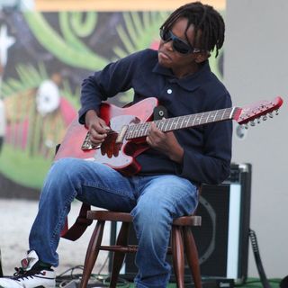 Miles sitting on stage playing guitar.