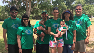 Sarah Koehnemann (in the middle with floral shorts, holding her niece) with her husband, mom (affected), dad, sister (affected) brother in law, niece and nephew during 2019 VisionWalk.