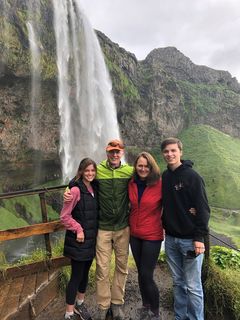 Sean with his wife and two children posing in front of a waterfall.