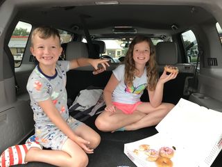 Hannah and her brother eating donuts in the car.