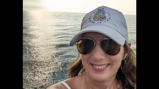 Michelle Glaze wearing a baseball hat and the ocean in the background.