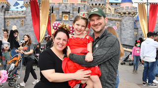 Dustin Buck with his wife and daughter in front of the Cinderella Castle in Disney World.