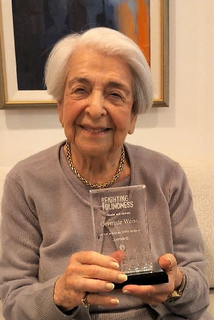 Photo of Gertrude Weiss on her 100th Birthday holding her award from the Foundation Fighting Blindness